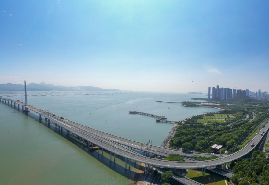 深圳灣大橋是繼羅湖、皇崗和沙頭角之后深圳第4條跨境通道，全長5545米，設(shè)南北兩個通航橋，主跨分別為210米和180米。大橋連接深圳蛇口與香港元朗，為中國公路干線網(wǎng)中唯一與香港連接的高速公路大橋，也是廣深沿江高速公路的咽喉。廣州與香港的距離因該橋建成通車縮短至100千米。大橋深圳側(cè)獨塔斜拉橋塔采用向香港側(cè)傾斜的斜塔，與香港側(cè)斜拉橋的橋塔向深圳側(cè)傾斜互相對應(yīng)，寓意深港兩地手牽手走向一起。圖為深圳灣大橋。
