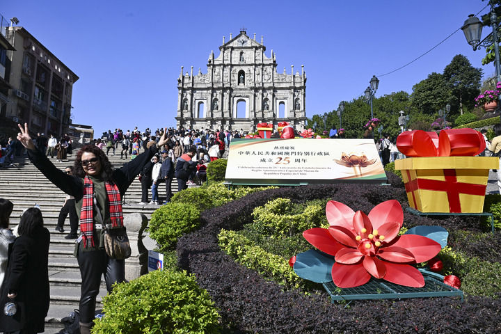 游客在澳門大三巴牌坊慶祝布景旁留影（2024年12月18日攝）。新華社記者 程一恒 攝