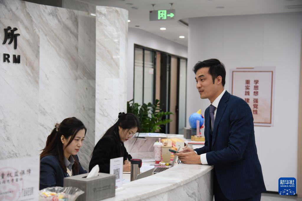 澳門律師阮嘉銳（右）在和同事交談（12月19日攝）。新華社記者 洪澤華 攝