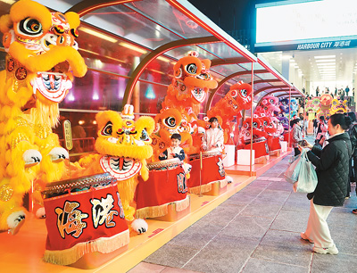 近日在香港維多利亞港畔，游客和醒獅合影。新華社記者 褚萌萌攝