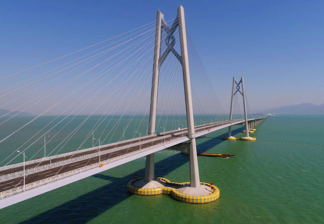 港珠澳大橋主體工程實(shí)行橋、島、隧于一體，總長(zhǎng)約29.6公里，穿越伶仃航道和銅鼓西航道段約6.7公里為隧道，東、西兩端各設(shè)置一個(gè)海中人工島（藍(lán)海豚島和白海豚島），猶如“伶仃雙貝”熠熠生輝；其余路段約22.9公里為橋梁，分別設(shè)有寓意三地同心的“中國(guó)結(jié)”青州橋、人與自然和諧相處的“海豚塔”江海橋，以及揚(yáng)帆起航的“風(fēng)帆塔”九洲橋三座通航斜拉橋。圖為寓意三地同心的“中國(guó)結(jié)”青州橋。